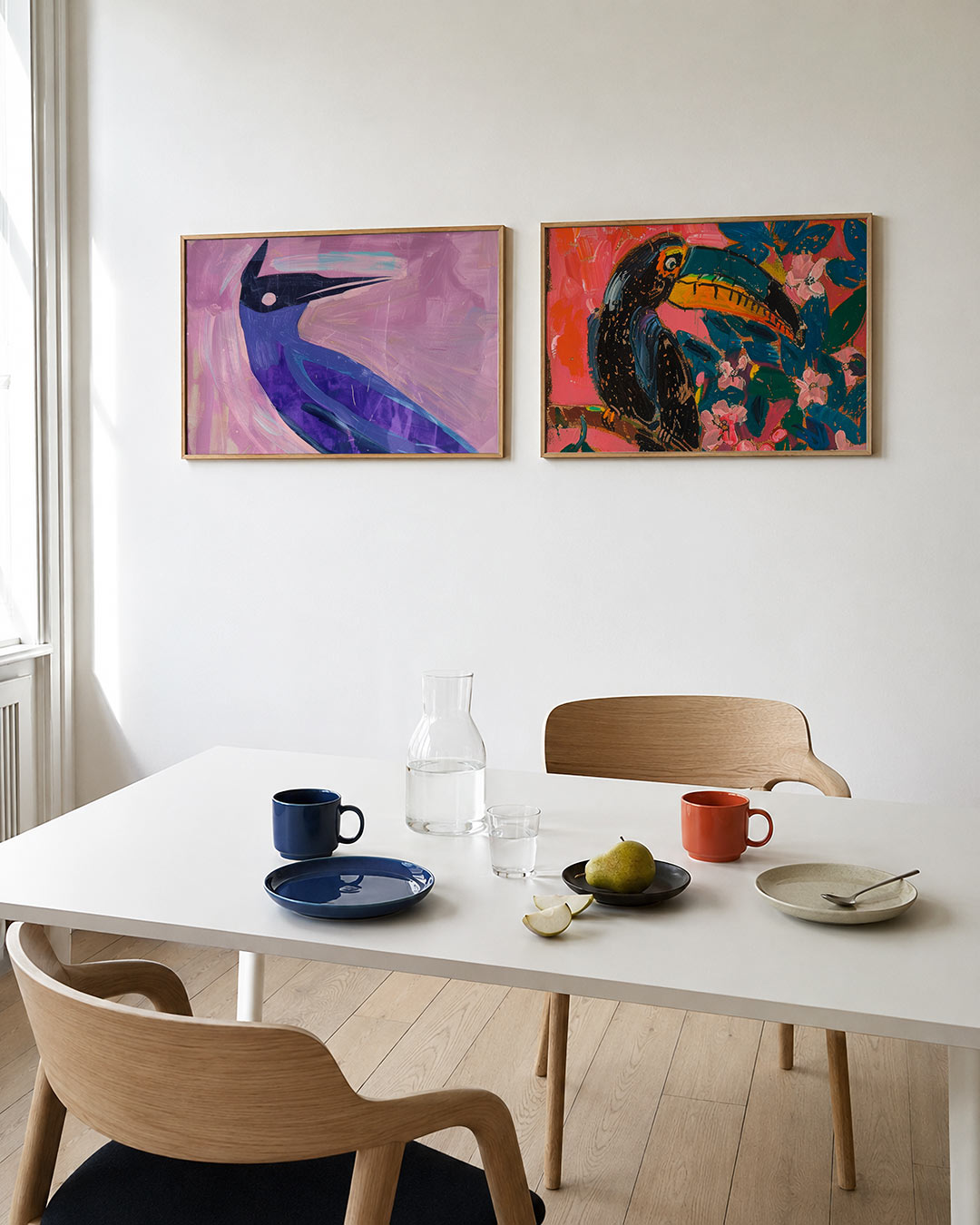 Twee liggende posters met een speelse vogelvorm in blauw en paars tegen een roze achtergrond, aan de muur in een interieur