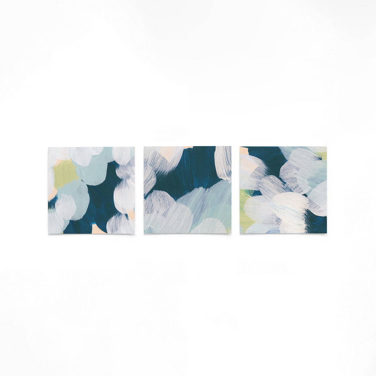 Drie vierkante posters met blauw witte penseelstreken op een gebroken witte achtergrond