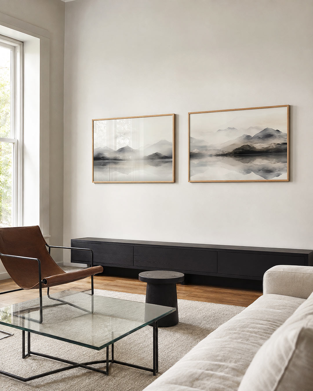 Twee liggende posters met een berglandschap met mist en reflecties in het water, aan de muur in een interieur