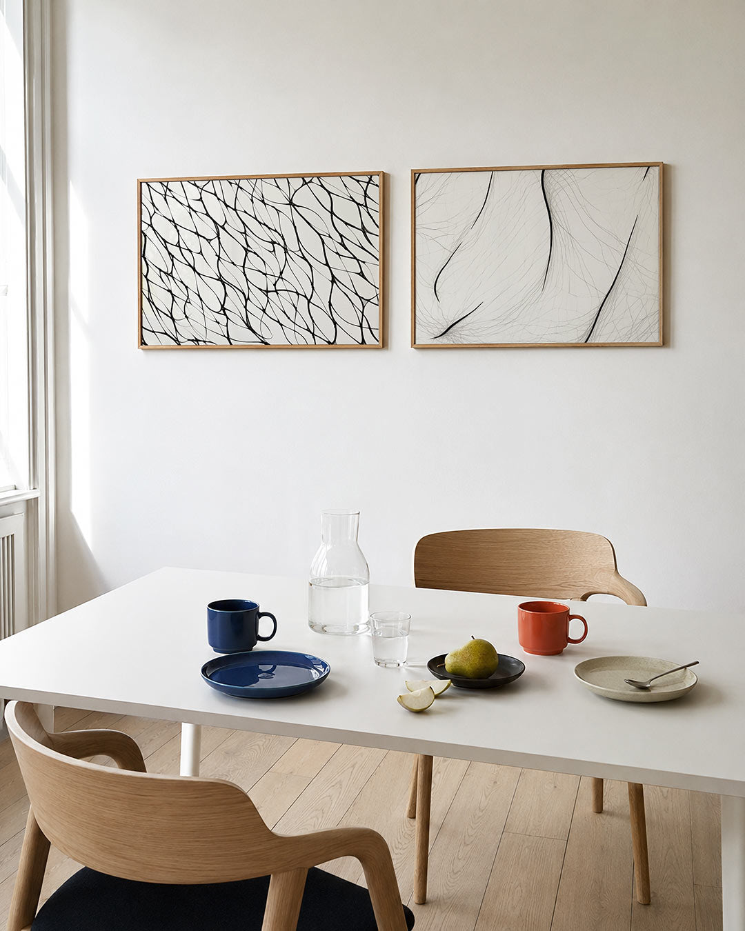 Twee liggende posters met zwarte, vloeiende lijnen op een witte achtergrond, aan de muur in een interieur