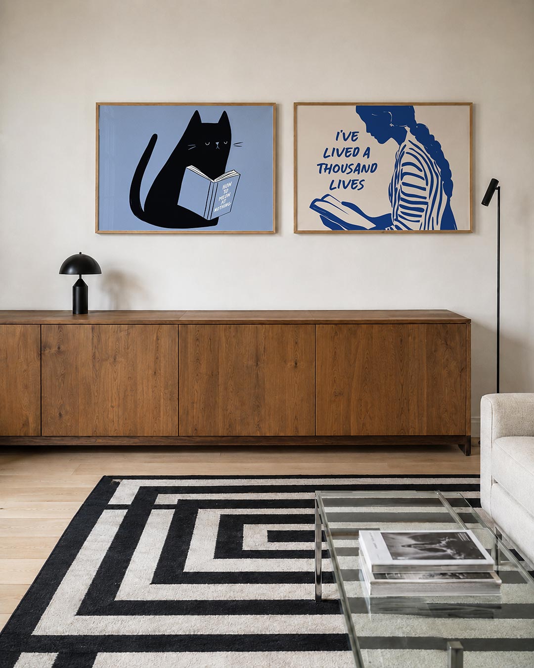 Twee liggende posters met een zwarte kat met een boek op een lichtblauwe achtergrond, aan de muur in een interieur