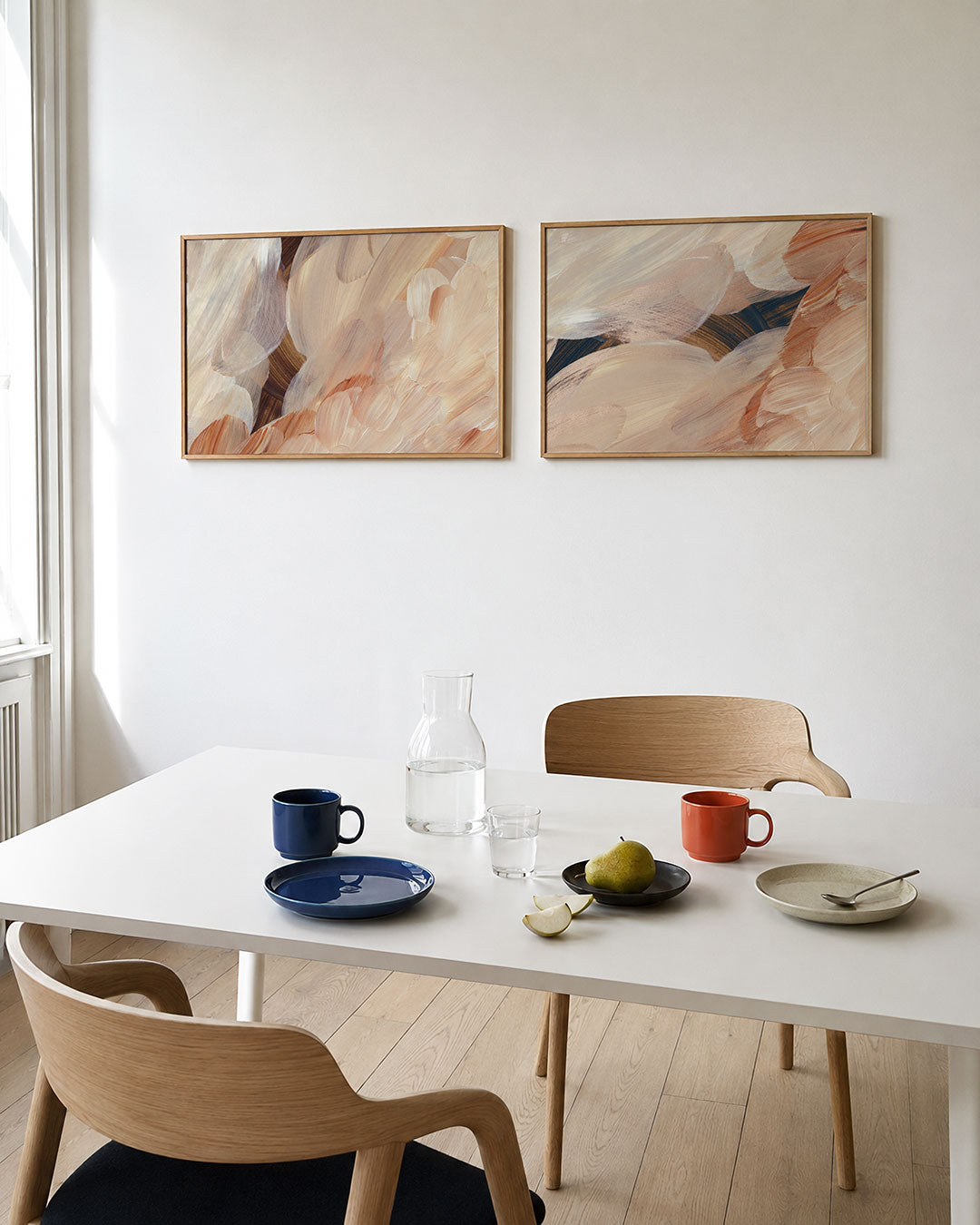 Twee liggende posters met vloeiende penseelstreken in warme, aardse tinten, aan de muur in een interieur