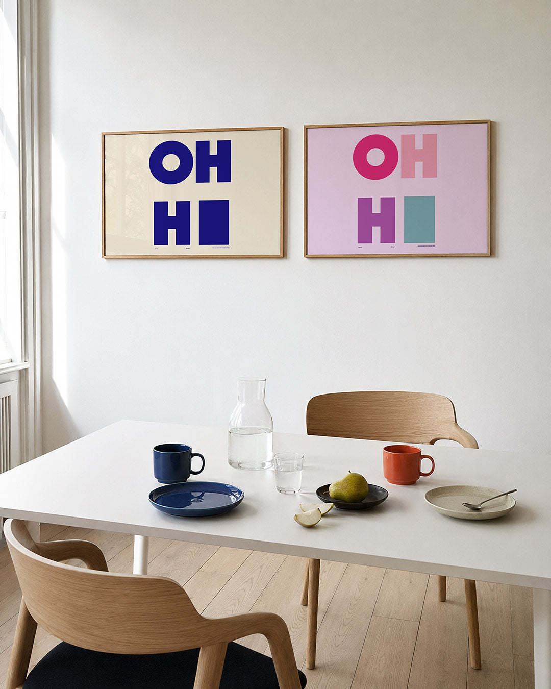 Tweedelige posterset met grote, blauwe letters op een lichte achtergrond, getoond in een interieur