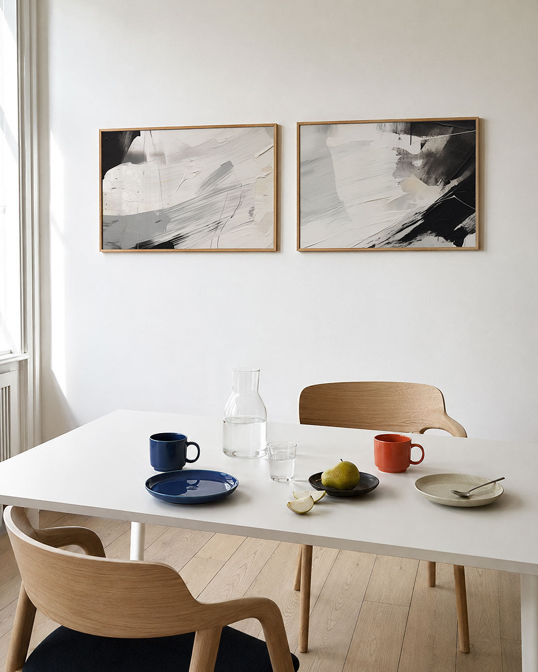 Twee liggende posters met vloeiende witte en grijze kleurvlakken, aan de muur in een interieur