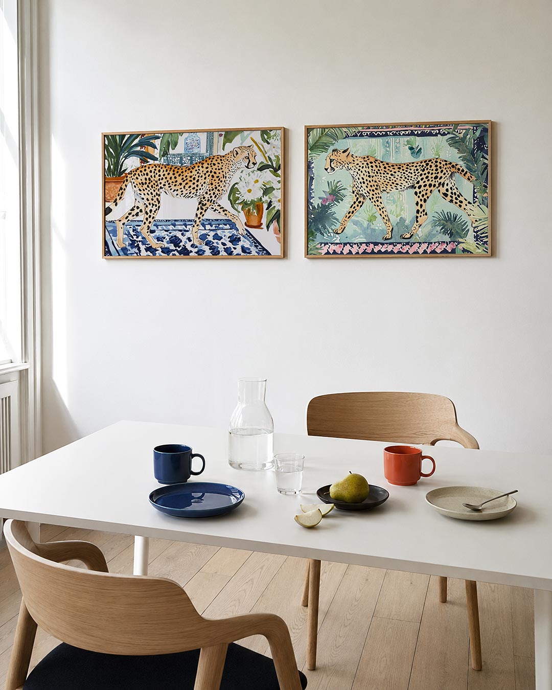 Tweedelige posterset met een sierlijke cheetah loopt over een blauw-wit patroon, getoond in een interieur