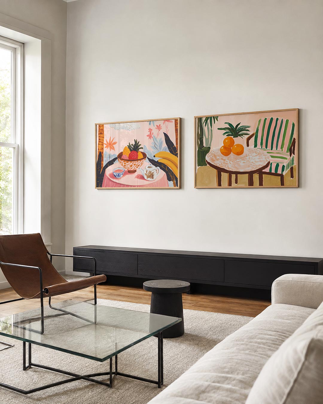 Twee liggende posters met een fruitschaal, bloemen en een theepot op een roze tafel, aan de muur in een interieur