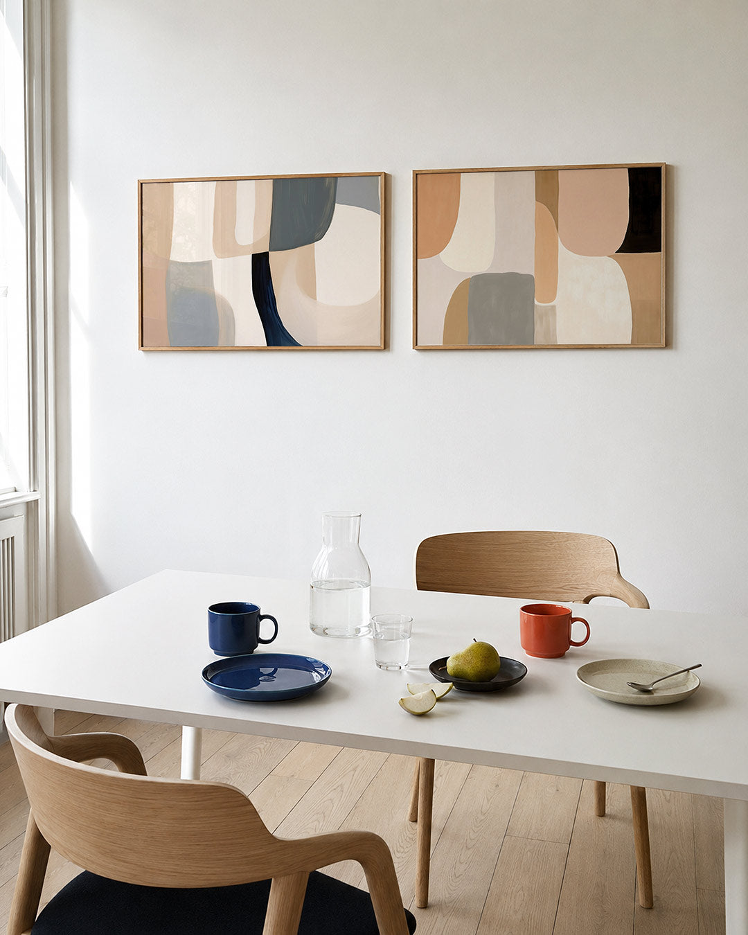 Twee liggende posters met zachte, vloeiende vormen in beige, blauw en grijs, aan de muur in een interieur