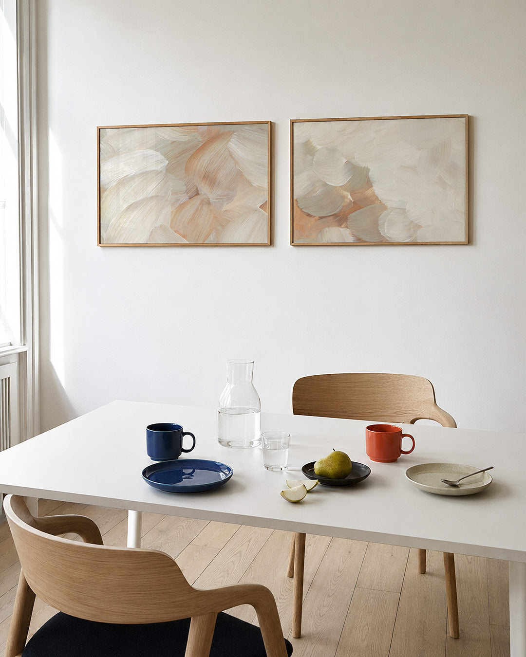 Twee liggende posters met vloeiende, overlappende penseelstreken in warme crèmetinten, aan de muur in een interieur