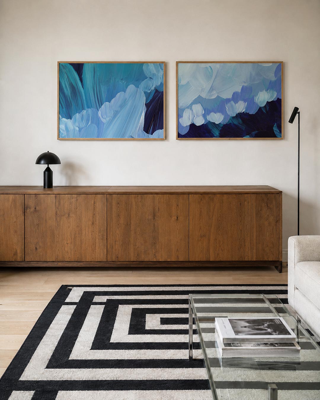 Twee liggende posters met vloeiende blauwe penseelstreken die elkaar overlappen, aan de muur in een interieur